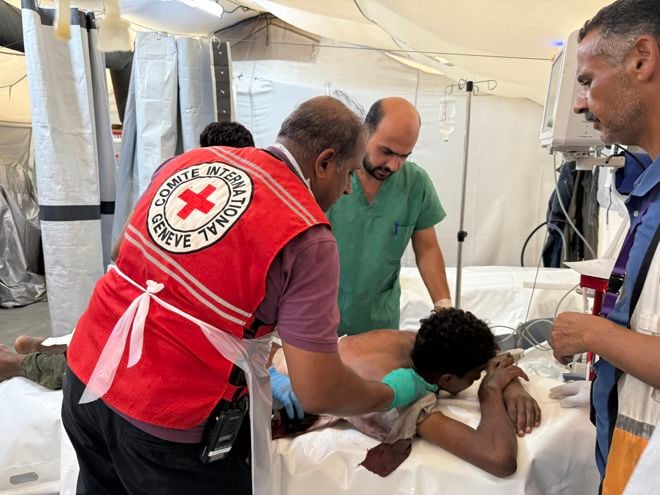 Doctors from Red Cross are treating a patient in the field hospital. 