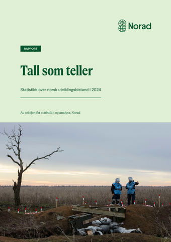 Bildet viser forsiden av en rapport med tittelen "Tall som teller" fra Norad, som handler om statistikk over norsk utviklingsbistand i 2024. Øverst på bildet er det en lys grønn bakgrunn med teksten i mørkegrønn skrift. Norads logo, som består av en stilisert globus, er plassert øverst til høyre. Under teksten er det et fotografi av et landskap med en enslig, bladløs tre til venstre og to personer i blå beskyttelsesvester til høyre. De står ved et område markert med rødt og hvitt, sannsynligvis et mineryddingsområde. Bakgrunnen viser en vidstrakt eng under en overskyet himmel.