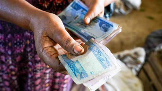 En person holder og teller flere sedler med etiopiske birr. 